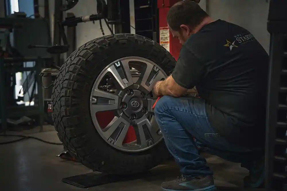 Technician at Starwood Custom Vehicles mounting an all-terrain tire in thier Northwest Arkansas Wheels and Tires Shop