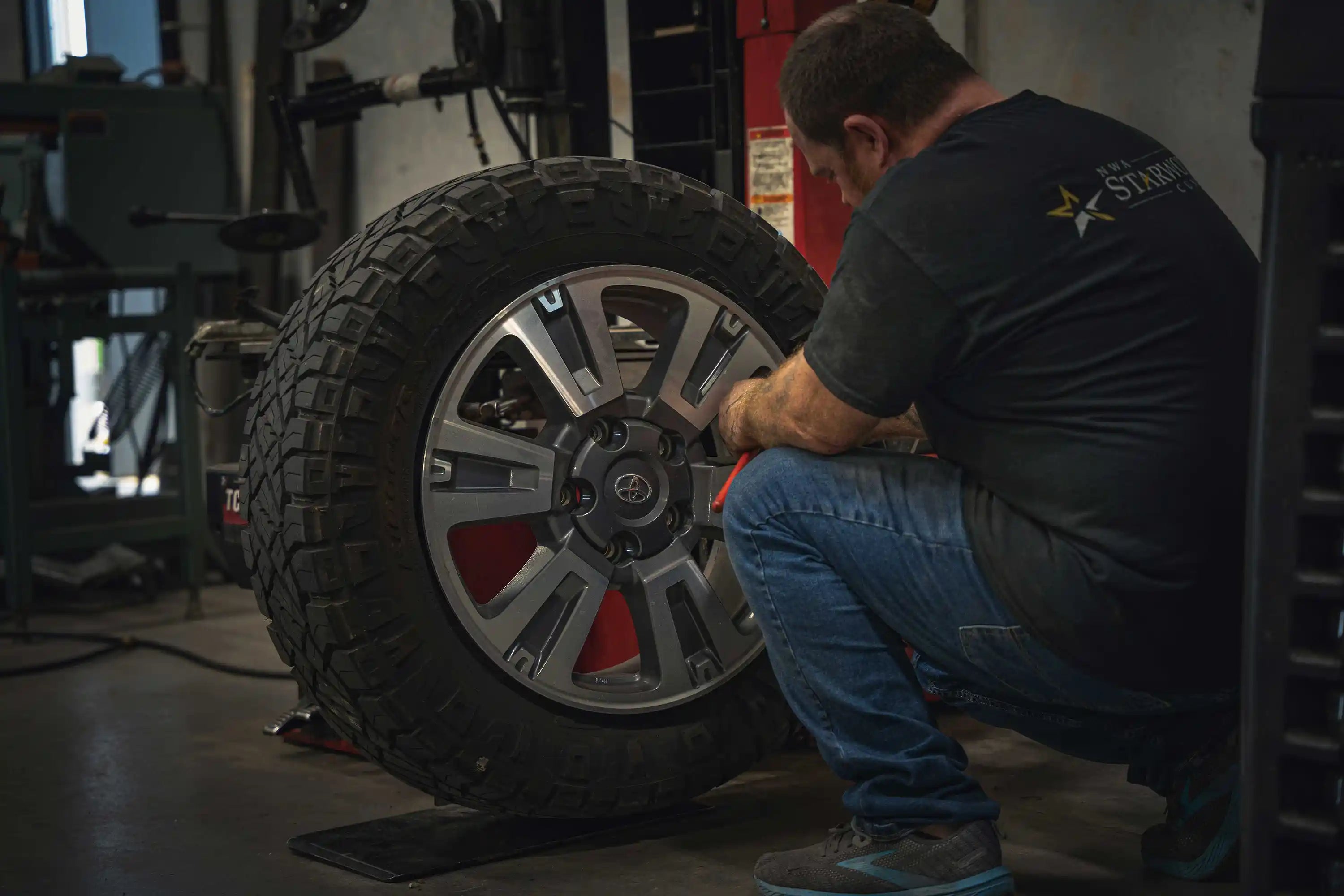Starwood Customs technichian mounting off-road tires on wheels at their shop in Northwest Arkansas providing wheel alignment, tire mounting, and installation services to Bentonville, Rogers, Springdale, Fayetteville, and the surrounding area.